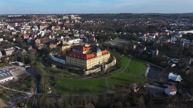 Flight in the north around Zeitz city center and Moritzburg Castle. Castle park in spring. Houses in the background illuminated by the sun. Small town in Saxony-Anhalt.