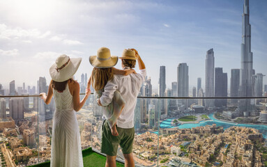 A elegant family on a city break vacation enjoys the panoramic view over the skyline of Dubai, UAE - 761694734
