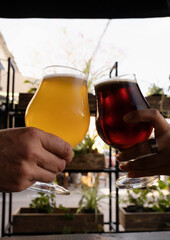 Celebration. Two young women hands toasting with beer cups filled with amber ale and golden honey beer.