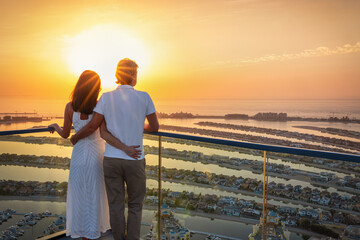 A romantic couple enjoys the panoramic sunset view of the Palm island at Dubai, UAE