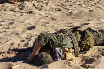 Historical reconstruction. Injured or dead World War II infantry  soldier  on the beach. View from...