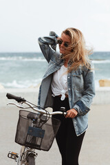 Fototapeta na wymiar Woman in a denim jacket enjoys a solo bike ride along a seaside promenade