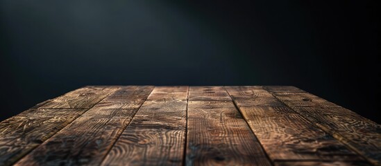 An empty hardwood table sits in a dimly lit room, contrasting with the black background. The wood grain and stain create a striking pattern against the dark backdrop