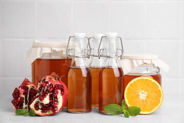 Tasty kombucha, fresh fruits and mint on white table