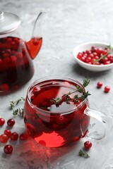 Delicious cranberry tea with thyme and berries on grey table
