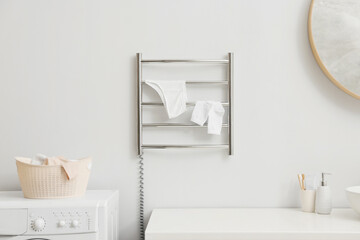 Heated towel rail with underwear and socks on white wall in bathroom