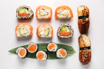 Different tasty sushi rolls on white background, flat lay