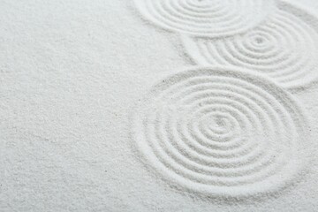 Fototapeta na wymiar Zen rock garden. Circle patterns on white sand, closeup. Space for text