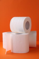 Soft toilet paper rolls on orange background, closeup