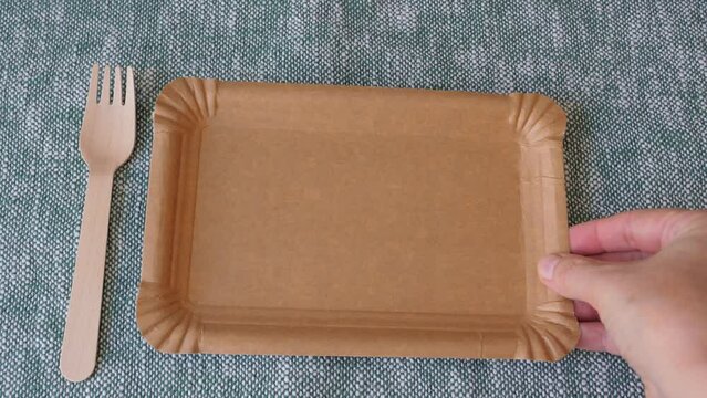Placing picnic wooden cutlery and paper plate. Natural materials. Eco friendly