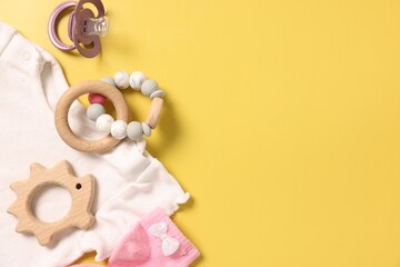 Different baby accessories on yellow background, flat lay. Space for text