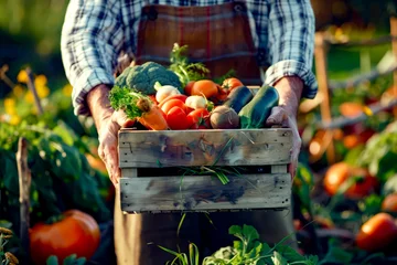 Fotobehang Man holding wooden crate filled with lots of assorted fruits and vegetables. © Констянтин Батыльчук