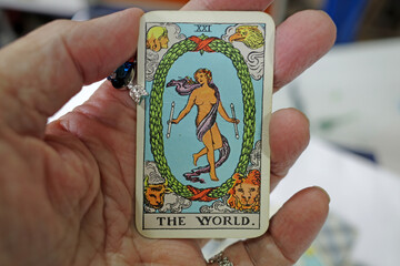 Hand of a fortune teller holding a tarot card in her hand. It's the world.  This card stands for...