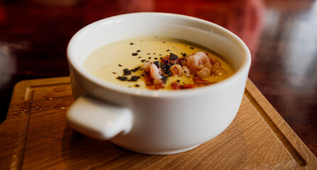 A bowl of soup is placed on a wooden cutting board, showcasing a simple yet comforting meal.