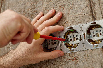 Man installing electrical outlet on the wall with a screwdriver - 761723502