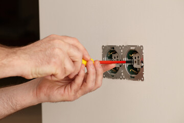 Man installing electrical outlet on the wall with a screwdriver - 761723507