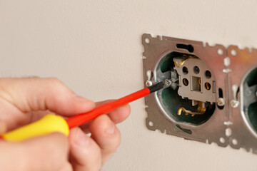Man installing electrical outlet on the wall with a screwdriver - 761723517