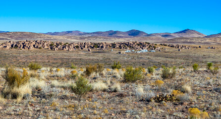 City of Rocks State Park in New Mexican Desert. View from the road with the mountains and blue sky on background.
