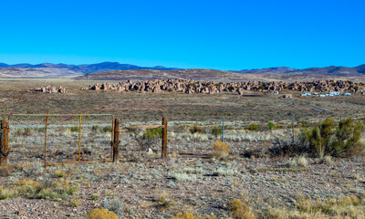 City of Rocks State Park in New Mexican Desert. View from the road with the mountains and blue sky on background.