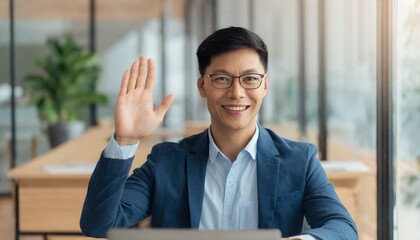 heerful young businessman greets with waving during virtual meeting, seated in a modern office environment, exuding a vibe of friendly professionalism