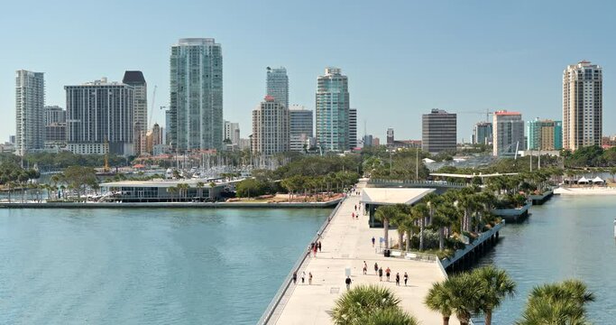 People walk on the St. Petersburg city coastal waterfront St. Pete Pier boardwalk path on Florida's Gulf Coast