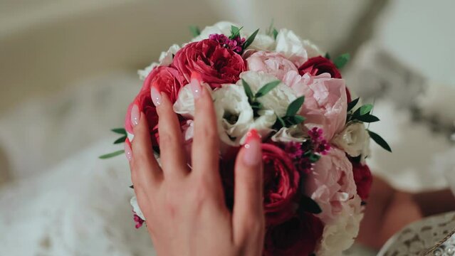 The girl holds a bouquet of fresh flowers in her hands and strokes its petals. She gently runs her fingers over the flowers.