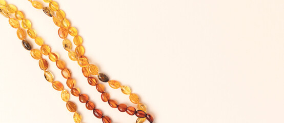 Banner with amber beads laid on a beige background. Place for text.