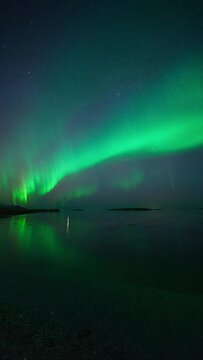 Northern lights drawing beautiful lines in the sky that mirrors in a reflective fjord in Mjelle, Bod&oslash;.
