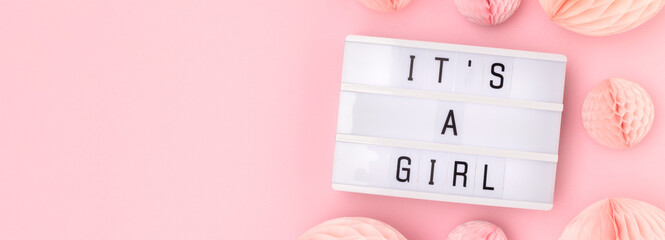 Banner with quote It's a girl. Lightbox with letters and tissue paper balls in a pink color. Baby...