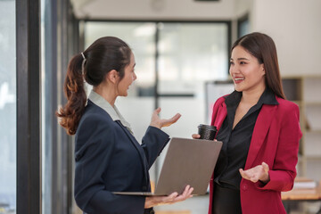 Two women in business suits are talking to each other