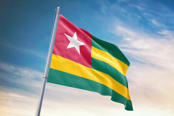 Waving flag of Togo in blue sky. Togo flag for independence day. The symbol of the state on wavy fabric.