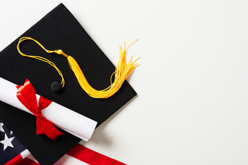 Flat lay composition with graduation cap, US flag and diploma on white background.