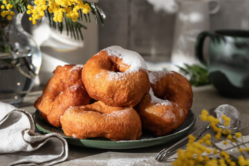 Delicious homemade crumpets or fried donuts sprinkled with powdered sugar on gray tile kitchen background in hard light
