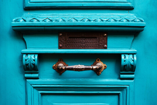 Carved beautiful door handle on an old turquoise painted door close-up