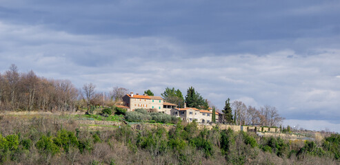 Several houses placed on a green hill in Istria on cloudy day