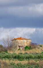 One lonely stone house placed on a green hill in Istria on cloudy day