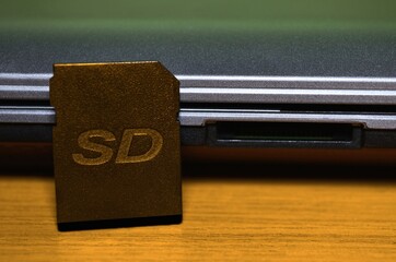 SD memory card near card reader in laptop on table in beautiful classic style