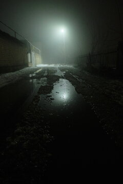 Night street with a glowing street lamp at its end, photo with a dramatic mood.
