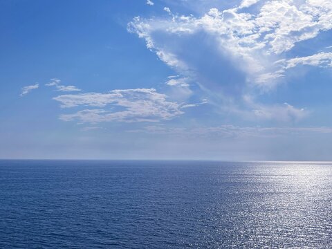 Blue sea shiny calm water and sky clouds