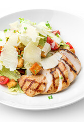 Caesar salad with grilled chicken breast, cherry tomatoes, croutons, parmesan cheese, lettuce in plate isolated on white background. Healthy food, top view