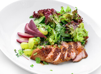 Healthy salad with medium rare beef steak, pear, grapes, lettuce, arugula, and sauce in plate isolated on white background. Healthy food, top view