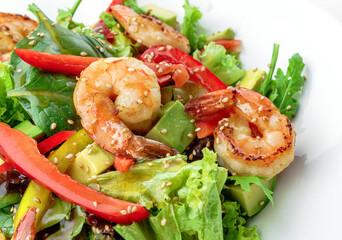 Healthy fresh salad with shrimp or prawns, avocado, lettuce, spinach, sesame, bell pepper and sauce in plate isolated on white background. Healthy food, top view