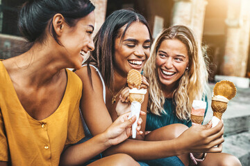 Happy women eating ice cream walking on city street - Happy group of friends enjoying summer...