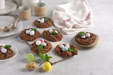 Easter chocolate cookies in the shape of Nests with sweet eggs on light table with mint leaves