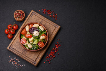 Fototapeta na wymiar Delicious fresh caprese salad with mozzarella, tomatoes, greens with salt, spices and herbs