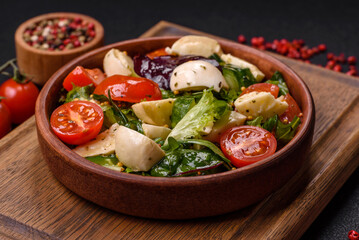 Delicious fresh caprese salad with mozzarella, tomatoes, greens with salt, spices and herbs