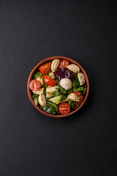 Delicious fresh caprese salad with mozzarella, tomatoes, greens with salt, spices and herbs