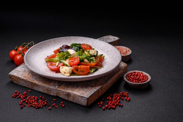 Delicious fresh caprese salad with mozzarella, tomatoes, greens with salt, spices and herbs