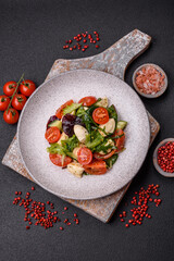 Delicious fresh caprese salad with mozzarella, tomatoes, greens with salt, spices and herbs