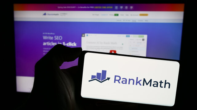 Stuttgart, Germany - 03-12-2024: Person holding mobile phone with logo of Indian WordPress SEO company Rank Math in front of business web page. Focus on phone display.